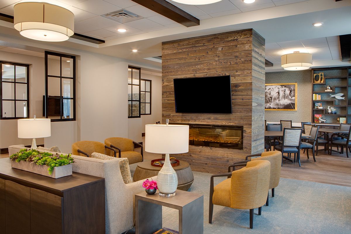 A modern living room with a cozy seating area, featuring a central fireplace and television.