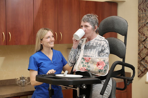 A nurse assists a patient during rehabilitation, ensuring she can enjoy a drink.