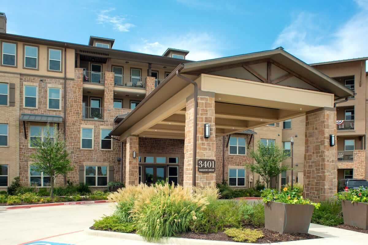 A modern residential building with a spacious covered entrance and landscaped surroundings.