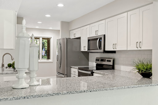 A beautifully renovated modern kitchen featuring sleek white cabinets and granite countertops.