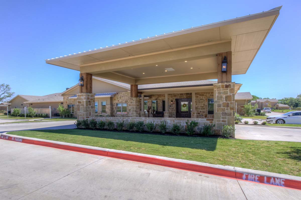A modern building entrance with a stone facade and well-maintained landscaping.