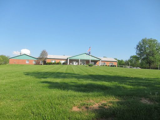 A serene view of a building set against a clear blue sky and lush green grass.