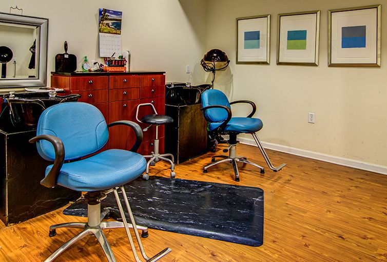 A cozy hair salon interior with blue chairs and wooden flooring.