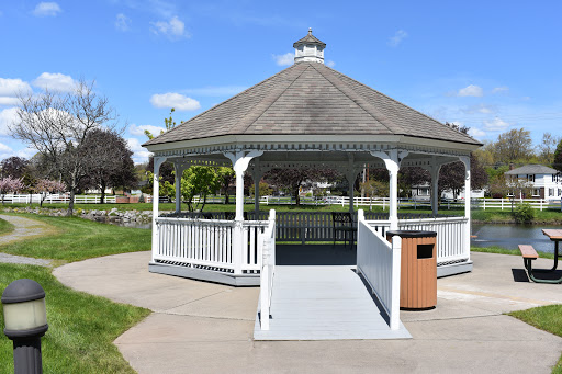 A charming gazebo in a park, surrounded by greenery under a clear blue sky.
