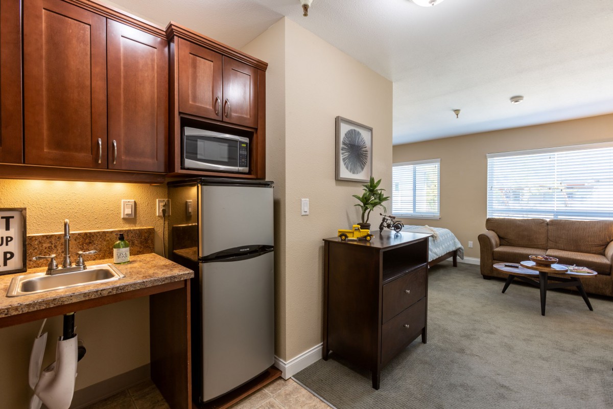 A cozy studio apartment featuring a kitchenette and comfortable living space.