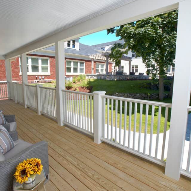 A cozy porch overlooking a suburban neighborhood, featuring wooden flooring and comfortable seating.