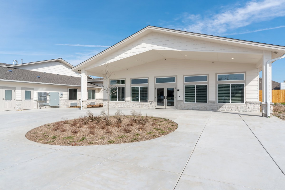 A modern commercial building with large windows under a clear blue sky.