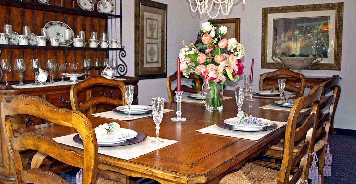 A beautifully set dining table with elegant dinnerware, floral centerpiece, and candles.