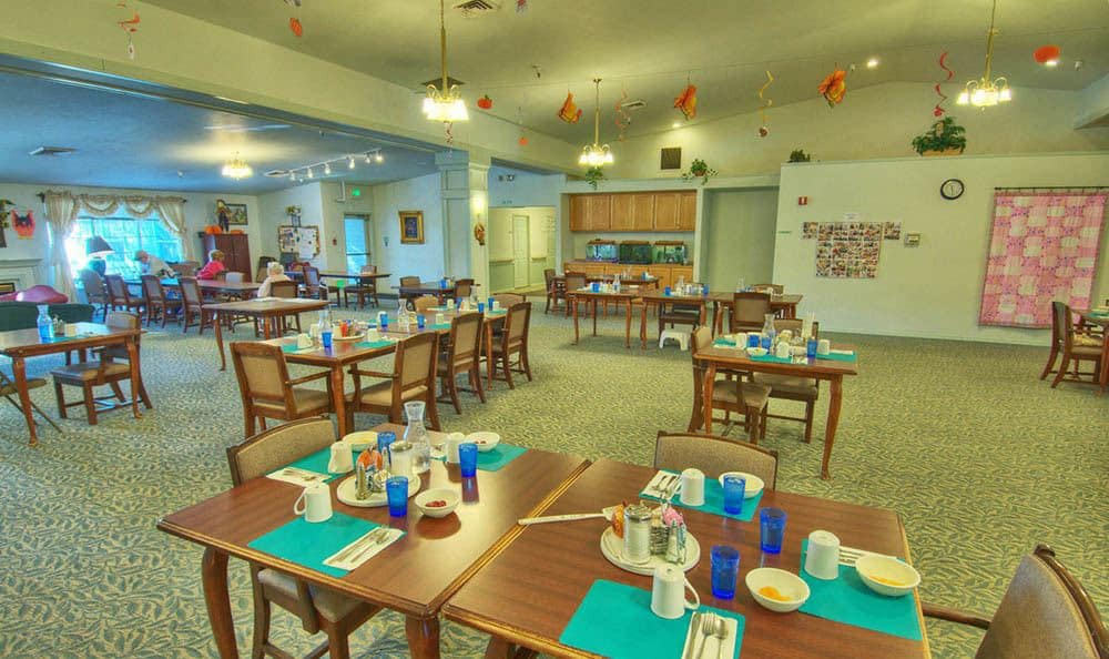 A spacious dining area with neatly arranged tables and chairs, featuring inviting place settings and warm lighting.