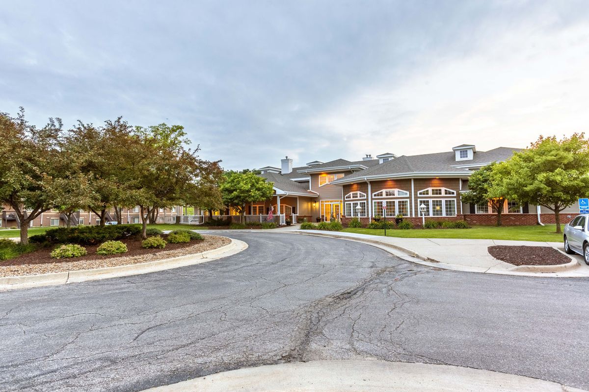 A large building with a circular driveway and landscaped surroundings under a cloudy sky.