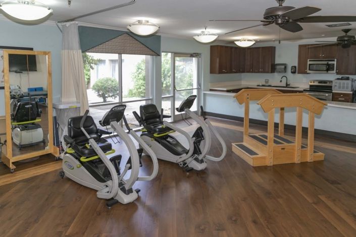 A neatly arranged indoor rehabilitation gym with exercise equipment.
