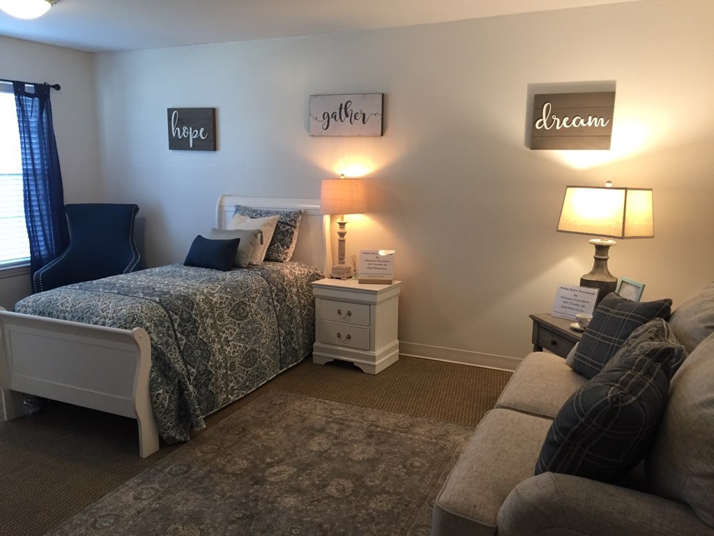 A cozy bedroom with a bed, sofa, and ambient lighting from lamps.