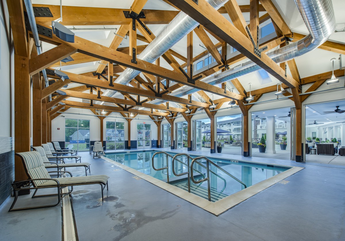 A modern indoor swimming pool with wooden beams and ample natural lighting.
