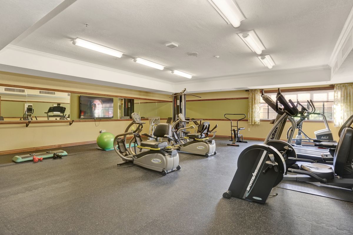 A spacious gym with various exercise equipment, including treadmills and elliptical machines.