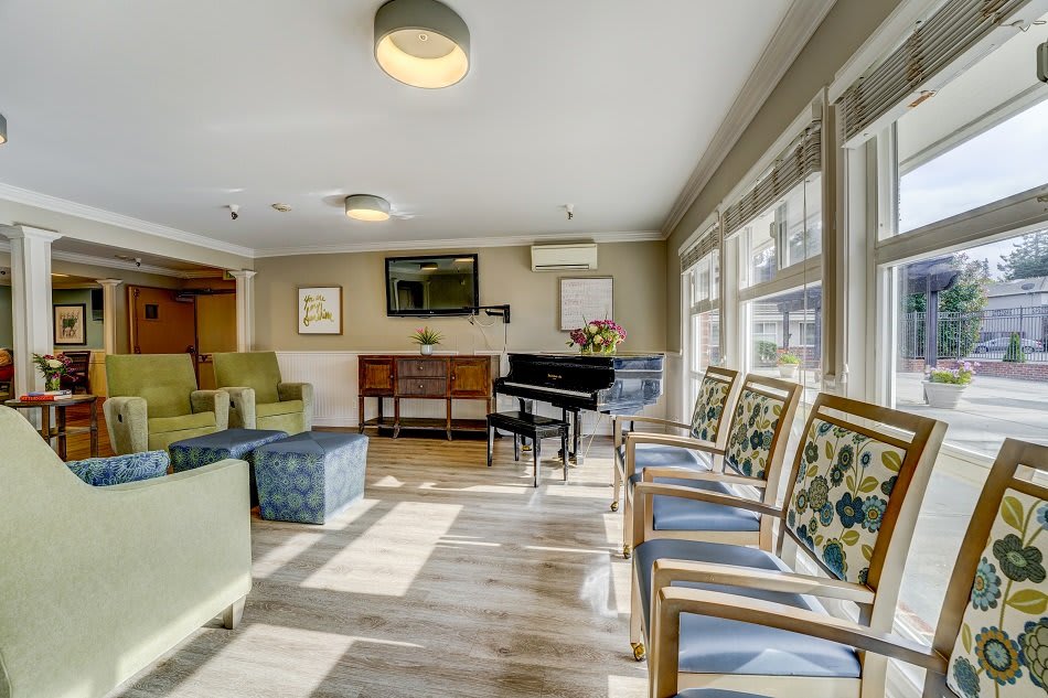 A cozy living room with a grand piano and ample seating, bathed in natural daylight.