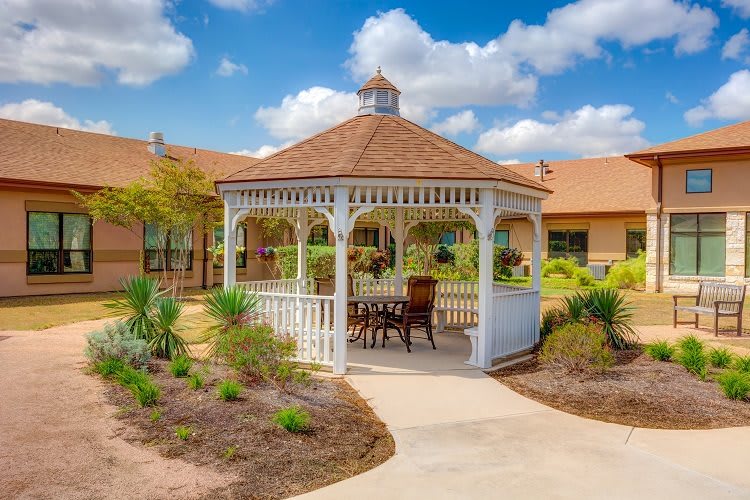 A charming gazebo surrounded by a landscaped garden on a sunny day.