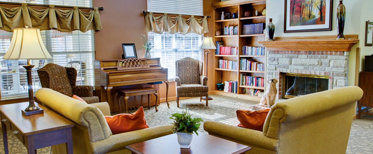A cozy living room with a piano, bookshelves, and comfortable seating.