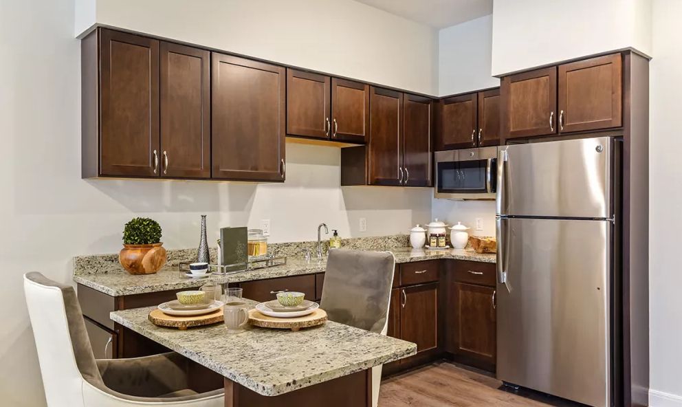 A modern kitchen with wooden cabinets, granite countertops, and stainless steel appliances.