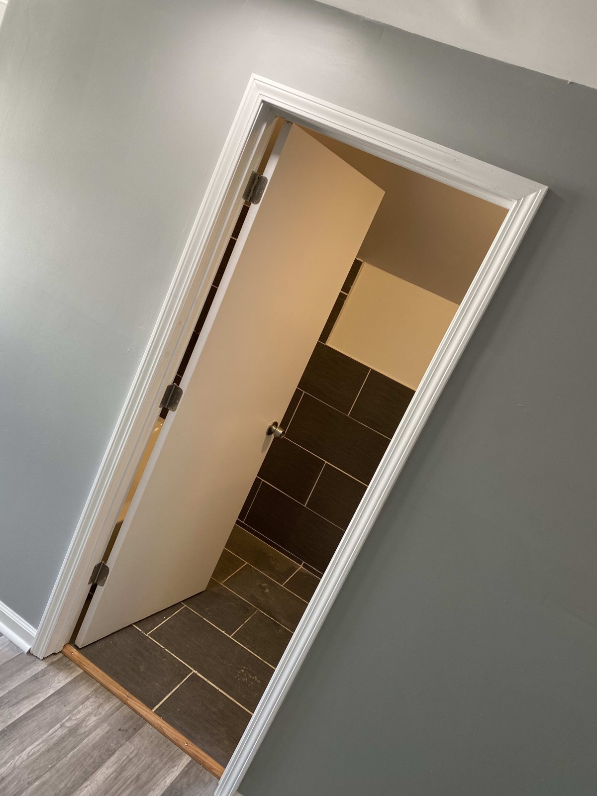 A doorway appears off-kilter, creating an optical illusion within a tiled room.