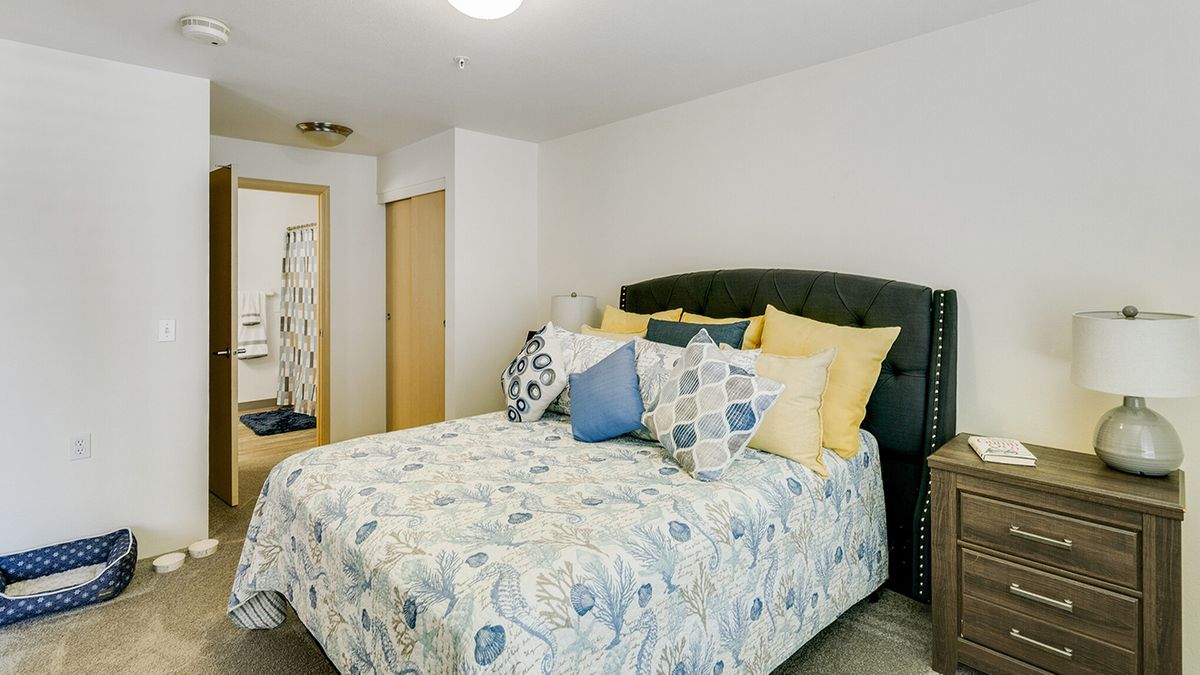 A cozy bedroom with a neatly made bed featuring patterned bedding and multiple decorative pillows.