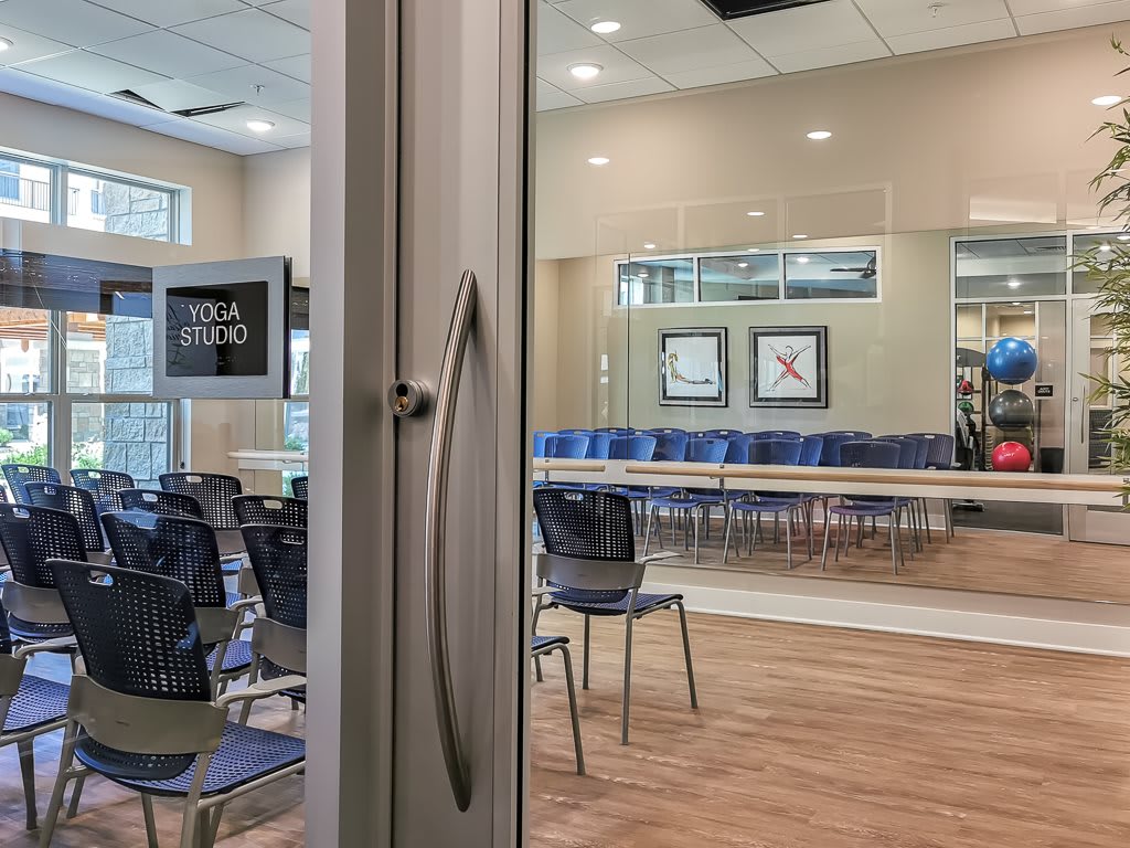 A modern meeting room equipped with chairs and tables, viewed through a glass door.