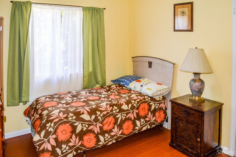 A cozy bedroom with floral bedding and a bedside lamp.