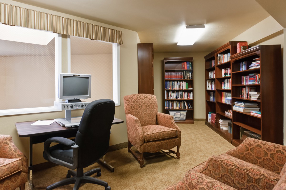 A cozy library corner with bookshelves, a computer desk, and comfortable seating.