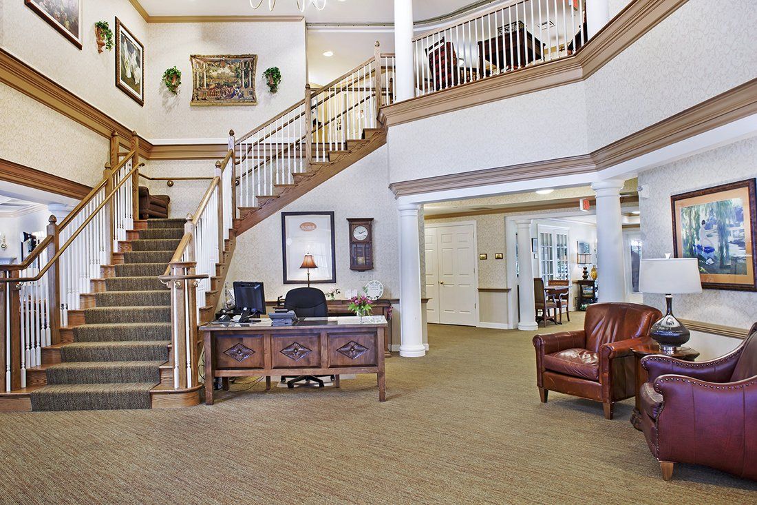 A spacious lobby area with a grand staircase, reception desk, and comfortable seating.