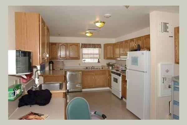 A cozy kitchen with wooden cabinets, featuring an oven, refrigerator, sink, and various appliances.