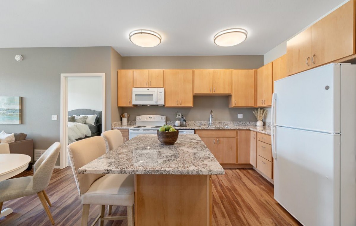 Modern kitchen with wood cabinets and a central island featuring marble countertops.