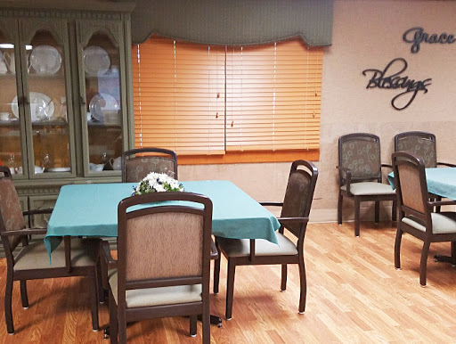 A cozy dining area featuring a table surrounded by chairs, with natural light filtering through the window blinds.