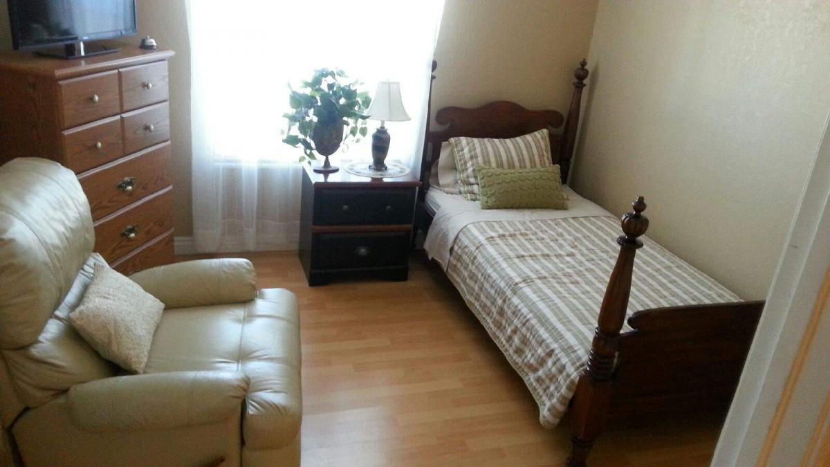A cozy bedroom with a single bed, nightstand, and natural lighting.