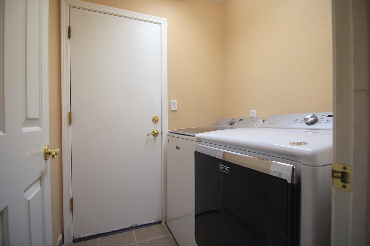 A small laundry room with a washer and dryer next to a closed door.