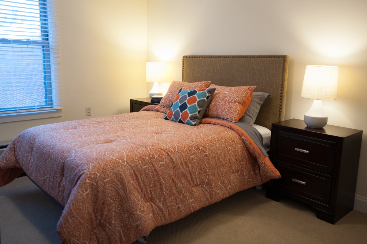 A cozy bedroom with a neatly made bed, two nightstands, and warm lighting.