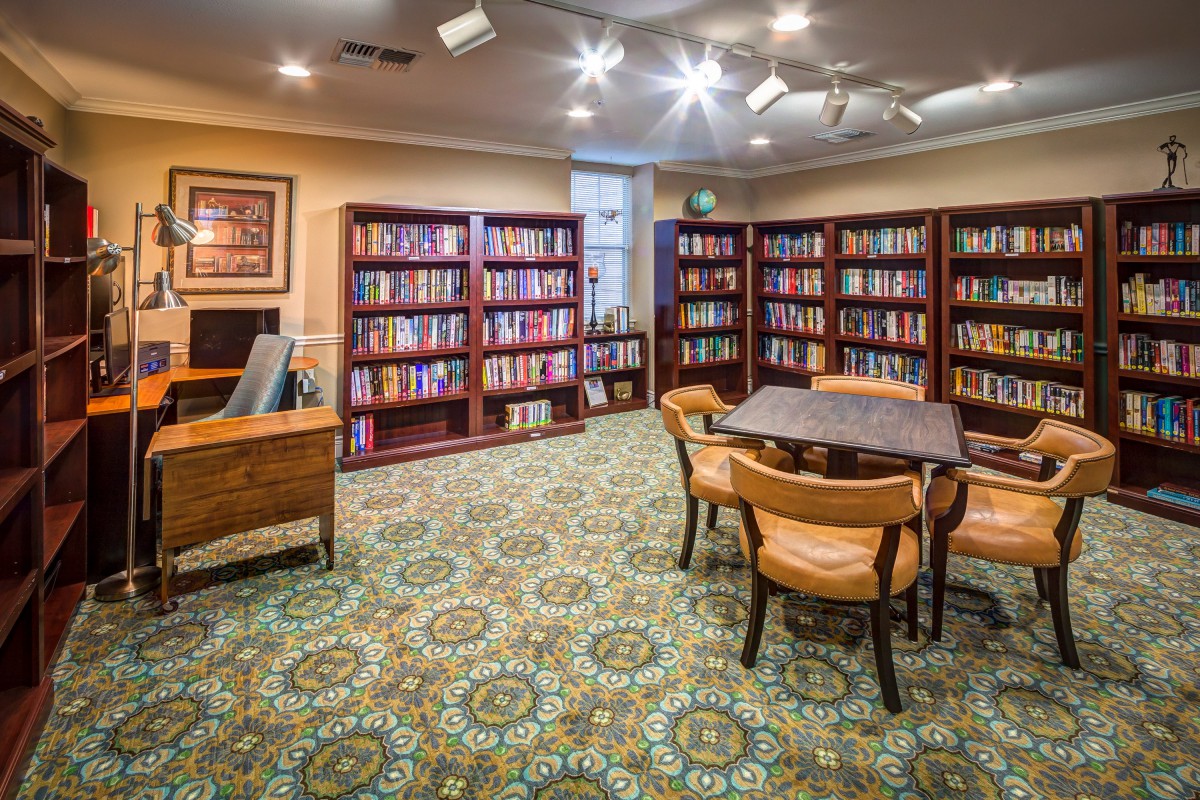 A cozy library reading room with bookshelves, a table, and chairs.