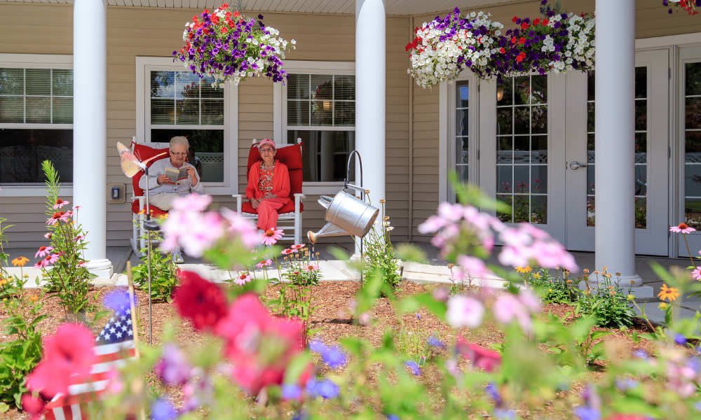 A cozy porch with hanging flower baskets, surrounded by a colorful garden.