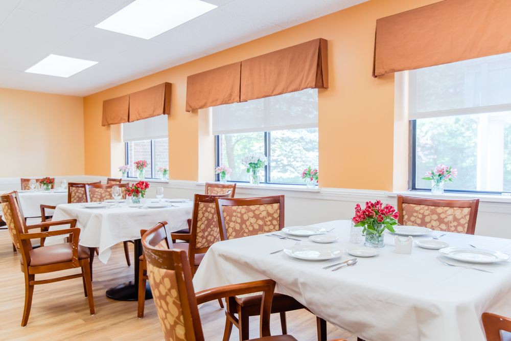 A bright dining area with neatly set tables and floral centerpieces.