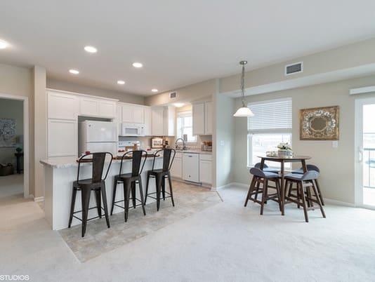 A modern kitchen with a dining area, featuring bar stools and an open layout.