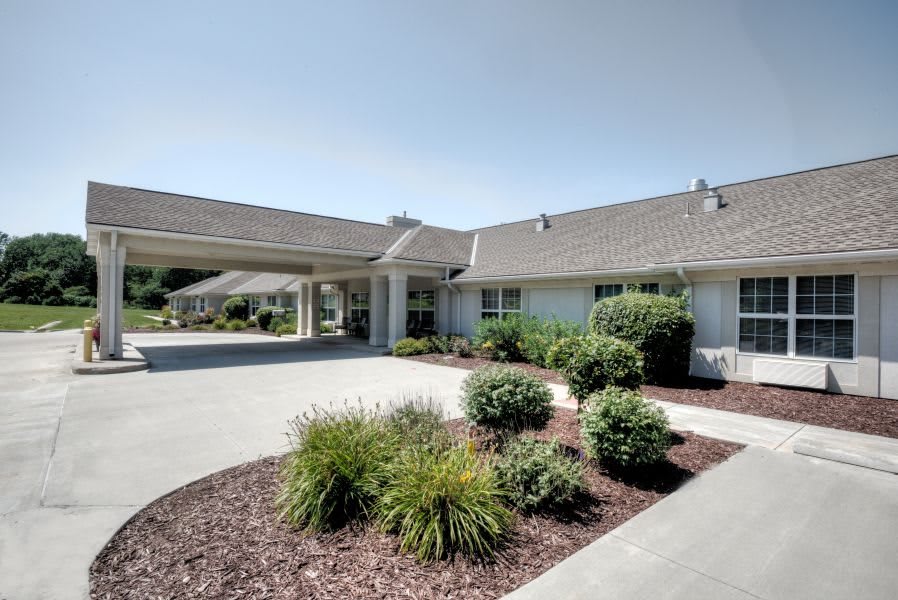 A well-maintained building with a landscaped driveway and green plants under a clear sky.