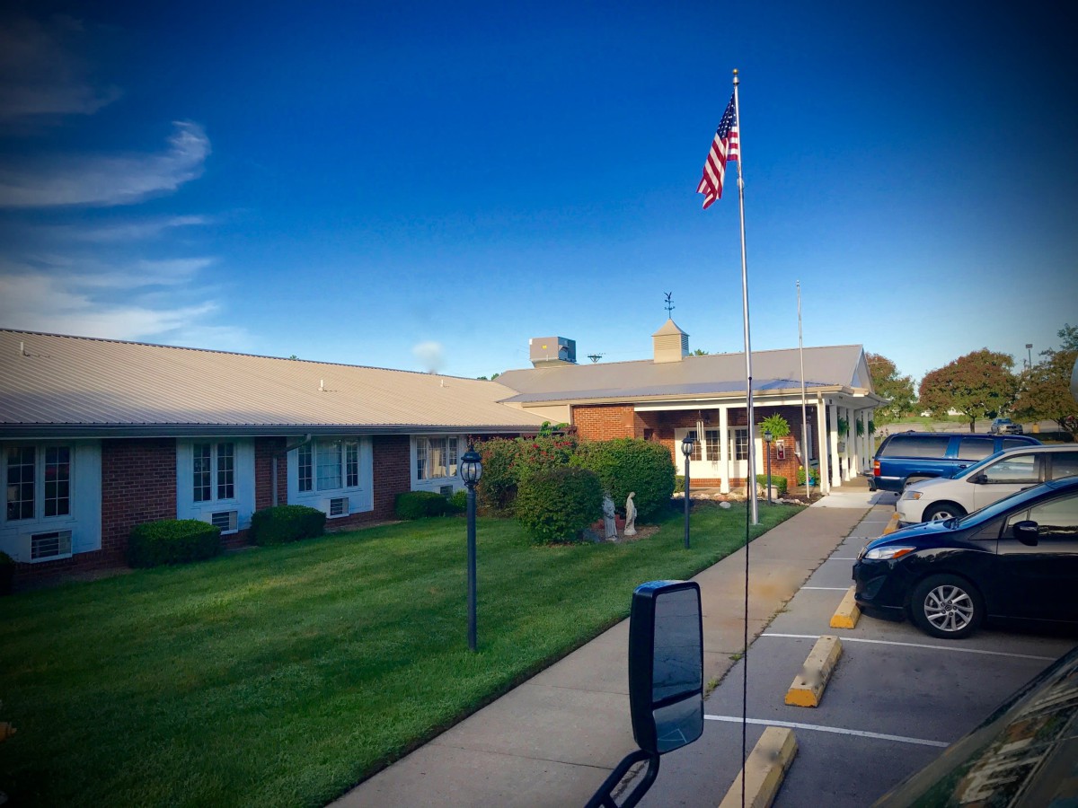 A building with an American flag, adjacent to a parking lot under a clear blue sky.