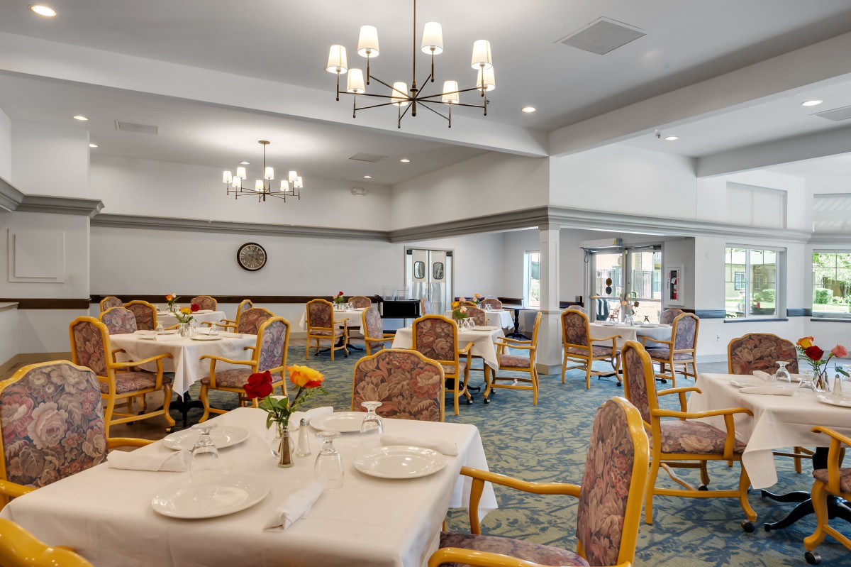 An elegant dining room featuring chandeliers and neatly arranged tables and chairs.