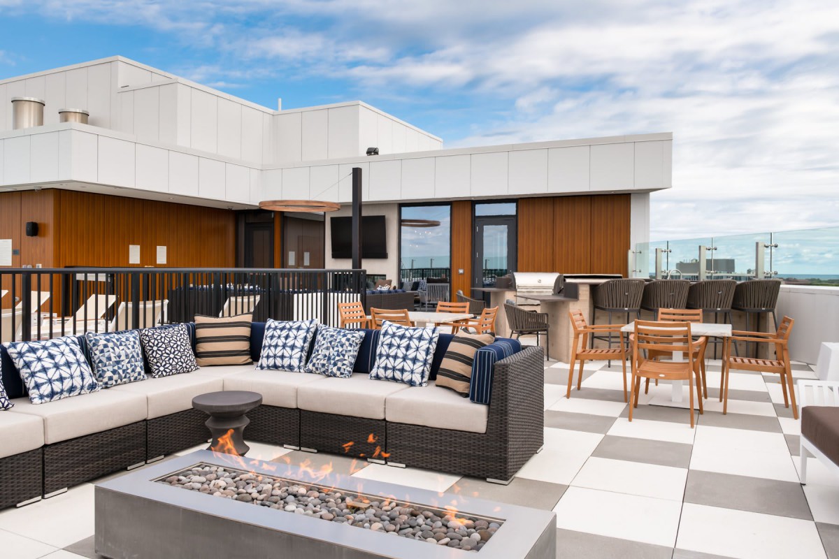 Modern rooftop patio with comfortable seating and a fire pit.