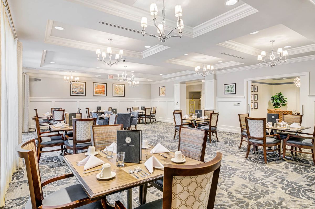 An elegant dining room with neatly arranged tables and chandeliers.