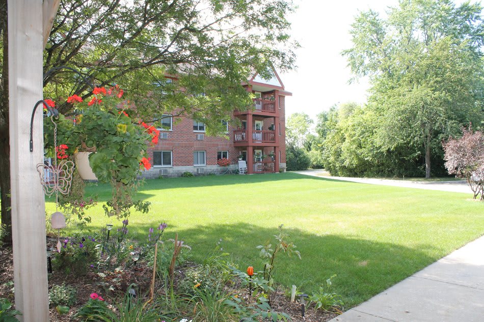 A brick building surrounded by a lush green lawn and trees.