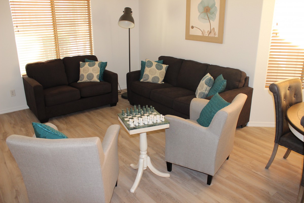 A cozy living room with sofas and armchairs, featuring a chess board on the table.