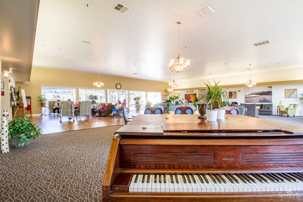 A spacious living room featuring a classic piano and elegant chandeliers.