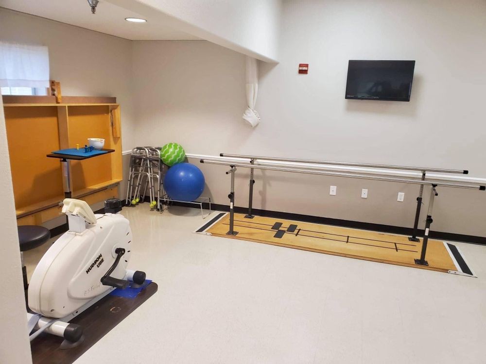 A physical therapy room equipped with parallel bars and an exercise bike.