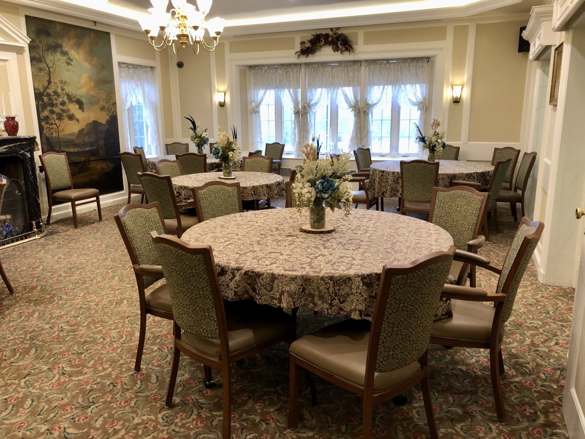 A well-decorated dining room with round tables, upholstered chairs, and a chandelier.