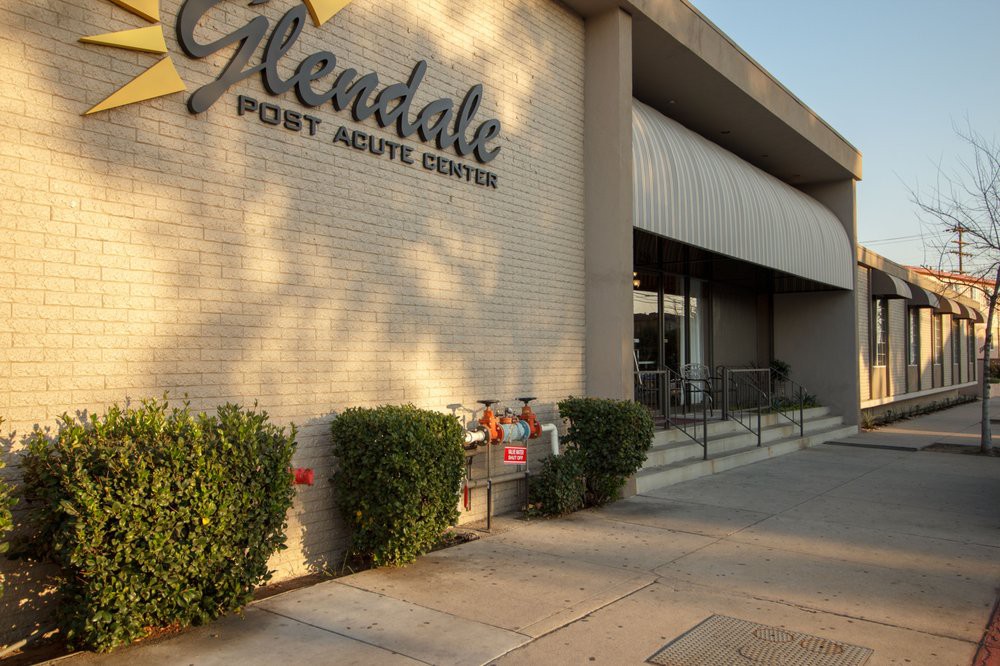 The entrance to Glendale Post Acute Center, featuring a sidewalk and greenery.