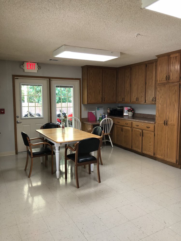 A kitchen area with wooden cabinets, a table, and chairs.